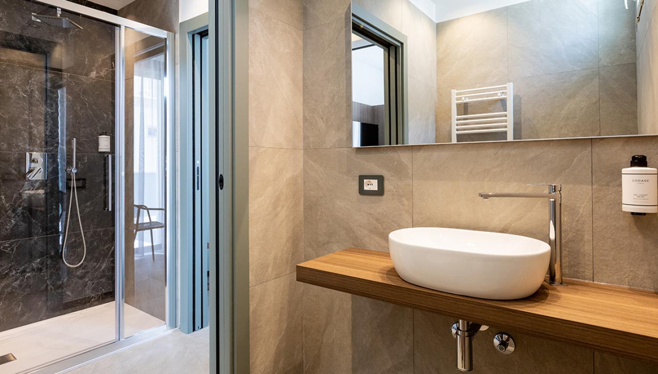 Bagno moderno con doccia elegante e lavabo su mensola in legno.